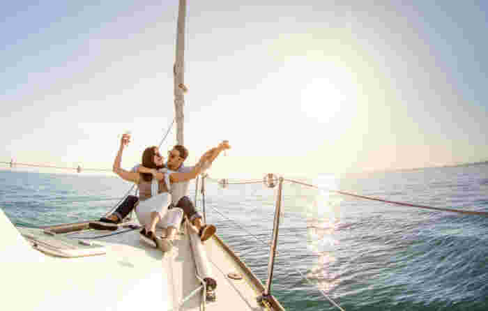 Young couple in love on sail boat with champagne at sunset - Happy people lifestyle on exclusive luxury concept - Soft backlight focus on warm afternoon sunshine filter - Fisheye lens distortion Private Boat Tours