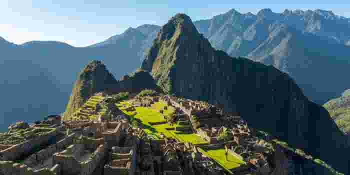 Panoramic view of Machu Picchu ruins surrounded by steep green mountains in the Andes.