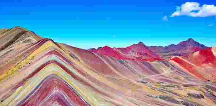 Wide view of Rainbow Mountain in Peru showing multicolored ridges stretching across the landscape.