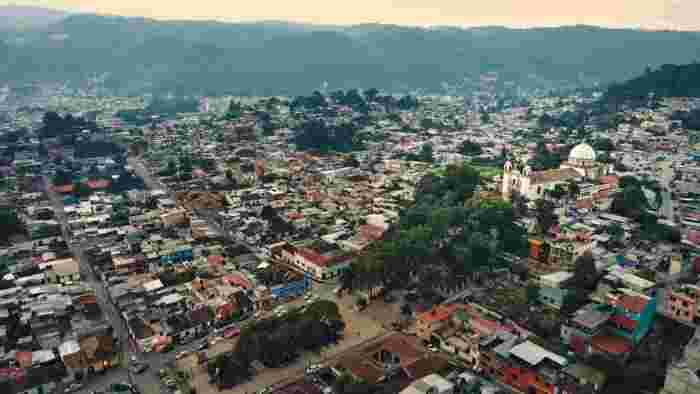 Aerial view of a town with a central church and surrounding buildings in a mountainous landscape in Arequipa region.