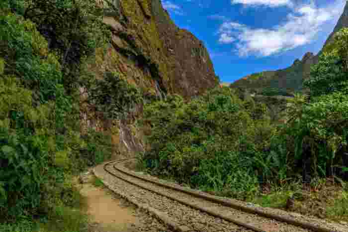 Railway tracks curving through lush green jungle and steep cliffs near Aguas Calientes.