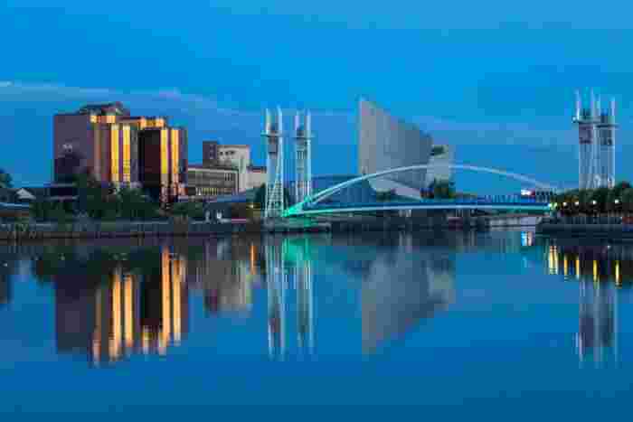 image Salford Quays in Manchester at dusk with the Lowry footbridge and Imperial War Museum North reflecting on the calm water.