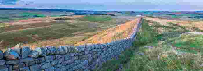 image Panoramic view of Hadrian's Wall stretching across open moorland and rolling hills in northern England.