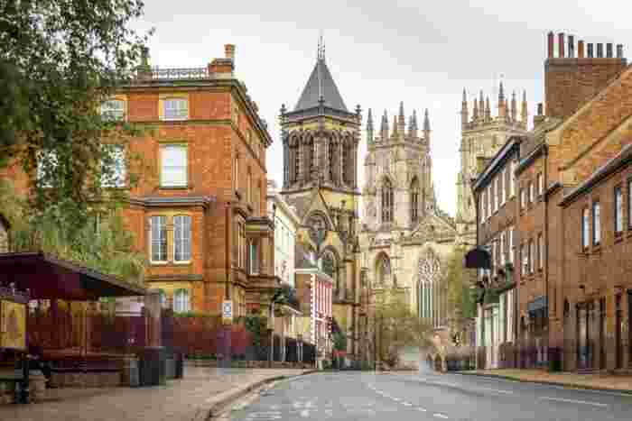 image A quiet street in York leading toward the Gothic towers of York Minster, flanked by red brick Victorian buildings.
