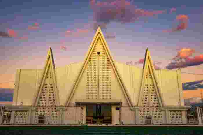 White modern church with sharp triangular architecture under a colorful sunset sky