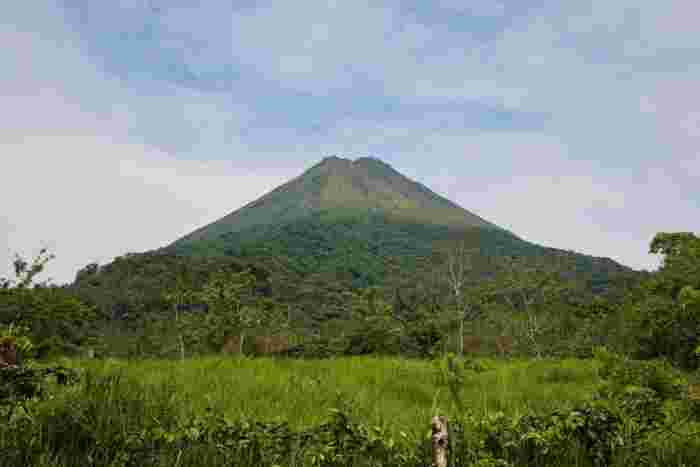 Arenal Volcano rising above lush green forest under a cloudy sky