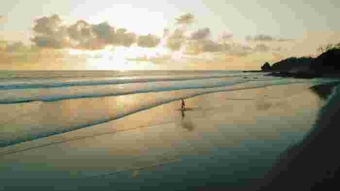 Sunset over a quiet Costa Rica beach with soft waves and reflections on wet sand