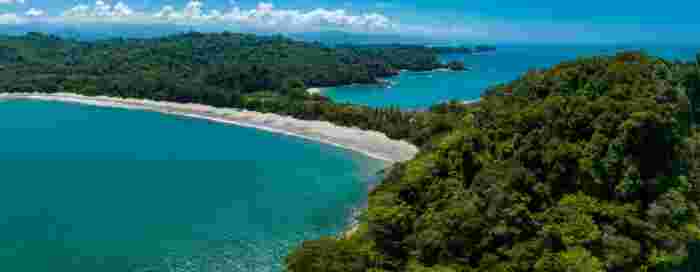 Aerial view of a long tropical coastline in Costa Rica with forest-covered hills and turquoise ocean