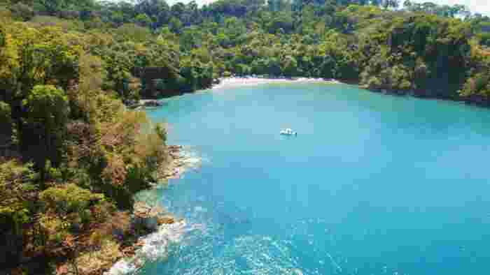 Aerial view of a sheltered bay in Costa Rica surrounded by dense rainforest and calm blue water