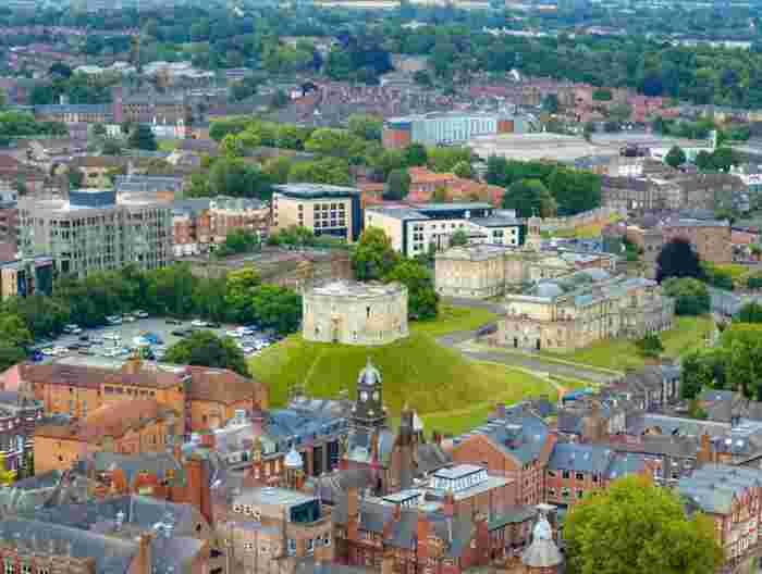 image Clifford's Tower, a medieval stone keep on a grassy mound, overlooking the rooftops of York with the Minster spires visible in the background.