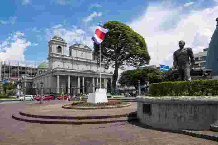 Plaza in San José with Costa Rican flag and historic church surrounded by trees