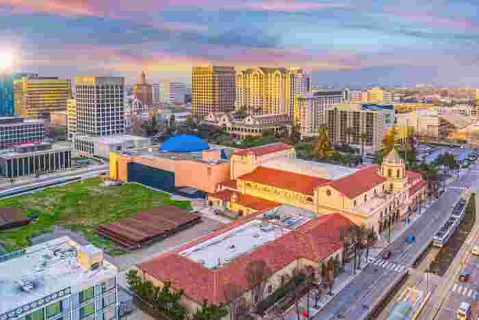 Cityscape of San José with colorful buildings and mountains under a sunset sky