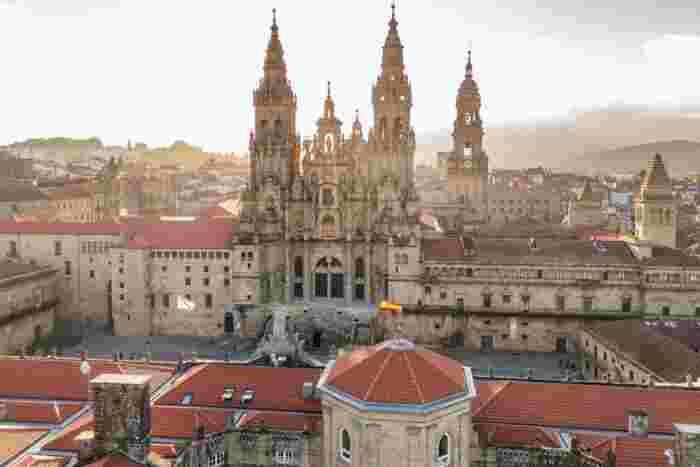 Santiago de Compostela Cathedral at sunrise with historic stone buildings and soft golden morning light. 