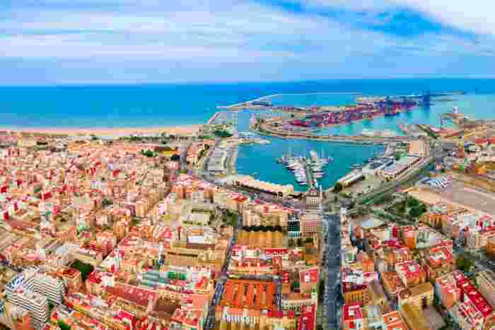 Aerial panorama of Málaga port and coastline with marinas, colorful city buildings, and the Mediterranean Sea. 