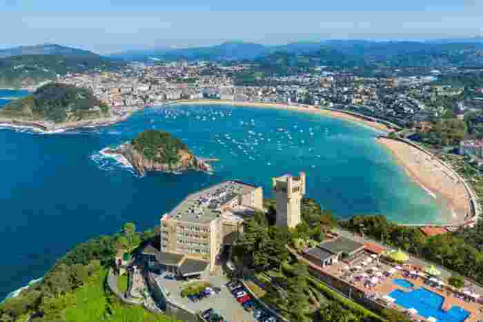 Elevated view of San Sebastián’s La Concha Bay with turquoise waters, beach promenade, and lush green hills. 