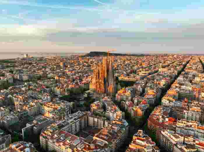 Aerial view of Barcelona with the Sagrada Família rising above the city grid at golden hour. 