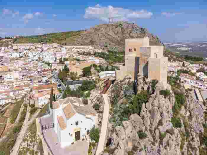 Hilltop castle overlooking the whitewashed town of Teba in Andalusia with rocky cliffs and countryside views. 