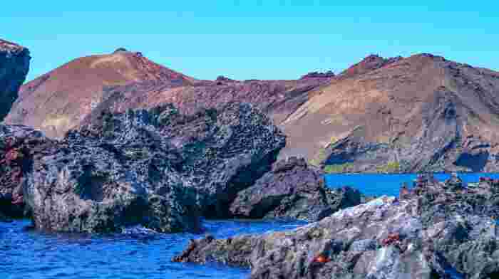 Rugged volcanic coastline and dark lava rock formations in the Galápagos Islands with deep blue Pacific waters 