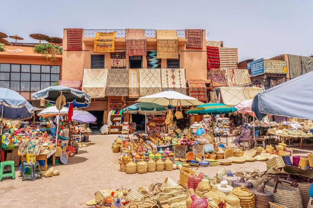 Handwoven rugs and woven baskets on display in a Marrakech souk