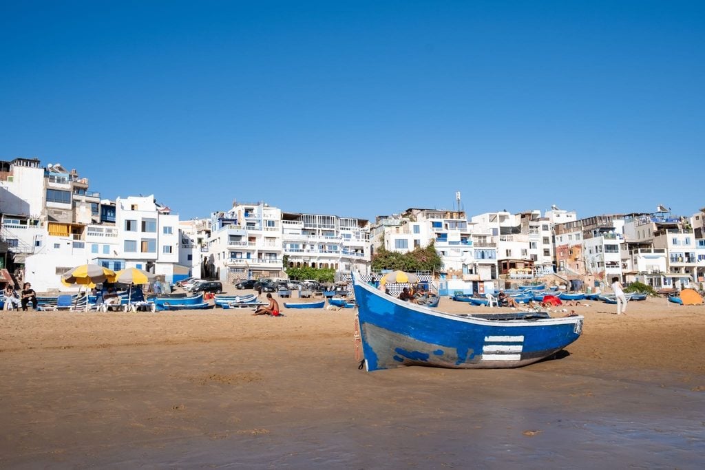 Blue fishing boats resting on the sandy beach of a Moroccan coastal town 
