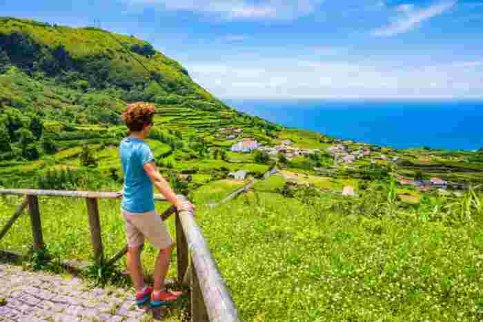 Young,Woman,Tourist,Standing,On,Wooden,Viewpoint,And,Looking,At Young woman tourist standing on a wooden walkway in the Azores, Portugal