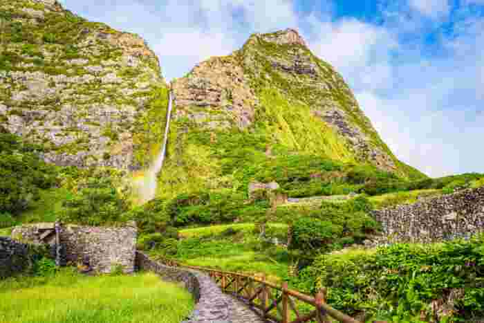 View,Of,Waterfall,Of,Poco,Do,Bacalhau,And,Green,Hills Waterfall of Poço do Bacalhau surrounded by green vegetation on Flores Island in the Azores, Portugal