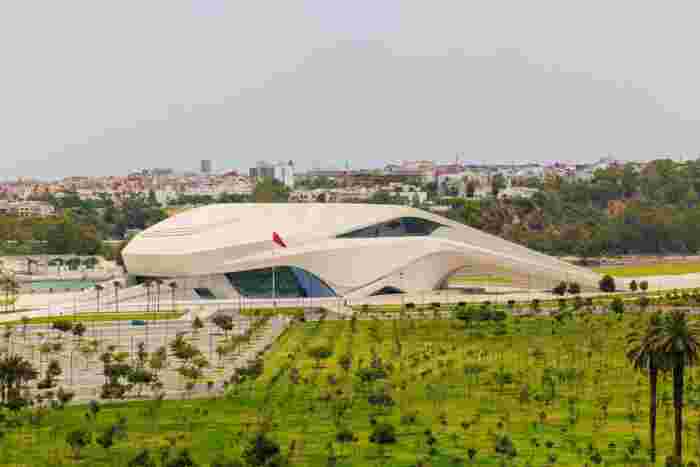 The Grand Théâtre de Rabat, a flowing white contemporary building surrounded by a landscaped park and young trees.