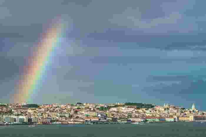 Lisbon,,Portugal.,A,Bright,Colorful,Rainbow,Stretches,Across,A,Dramatic Bright colorful rainbow stretching over Lisbon, Portugal