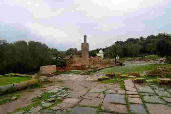 The ruins of Chellah in Rabat, with a stork nest on a minaret, crumbling walls and a stone path on a cloudy day.