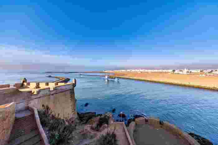 View from a Kasbah of the Udayas bastion over the mouth of the Bou Regreg River, with a boat heading out to sea and Salé's beach opposite.