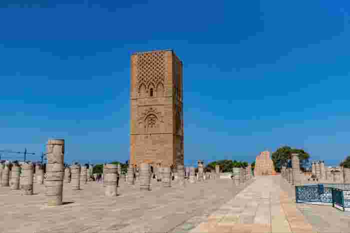 The unfinished Hassan Tower in Rabat, rising above rows of ancient stone column bases on a wide esplanade.